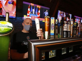 General manager Jason Reeb of The Cat 'n Fiddle Pub pours a beer as Premier Jason Kenney announces new restrictions in Calgary on Tuesday, Dec. 8. DARREN MAKOWICHUK/POSTMEDIA