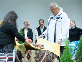 The NWMO’s Jessica Perritt, Section Manager for Indigenous Knowledge and Reconciliation, and Bob Watts, Vice-President of Indigenous Relations, gather the sacred bundle at the ceremony formalizing the NWMO’s Reconciliation Policy. SUBMITTED