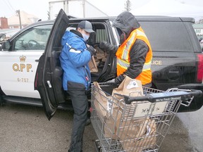 During Saturday's 12 Days of Giving food drive in Tillsonburg, Helping Hand Food Bank volunteers help unload an OPP cruiser 'crammed with food' collected during the Cram A Cruiser food drive at Sobeys. Another 12 Days of Giving drive-thru food drive will be held at the food bank next Saturday, Dec. 19, from 9-3. (Chris Abbott/Norfolk and Tillsonburg News)