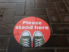 A physical distancing reminder sticker marks a spot for people to stand while awaiting service.

Gavin Young/Postmedia