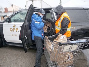 During last Saturday's 12 Days of Giving food drive in Tillsonburg, Helping Hand Food Bank volunteers help unload an OPP cruiser crammed with food after it was collected during their food drive.Another 12 Days of Giving drive-thru food drive will be held at the food bank Saturday from 9 a.m. to 3 p.m. (Chris Abbott/Norfolk and Tillsonburg News)