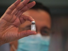 An employee holds up a vial of the Pfizer COVID-19 vaccine Monday at The New Jewish Home long-term care facility on Manhattan’s Upper West Side in New York. BRYAN R. SMITH/AFP via Getty Images