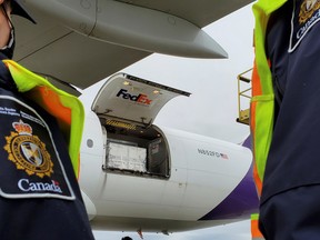 Canada Border Services Agency (CBSA) officers watch as the first shipment of newly authorized Moderna COVID-19 vaccine is unloaded from a Fedex cargo jet at a port of entry in Canada on Wednesday, Dec. 24,