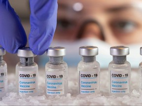 Woman holds vials labelled "COVID-19 Coronavirus Vaccine" over dry ice in this illustration taken, Dec. 5, 2020.