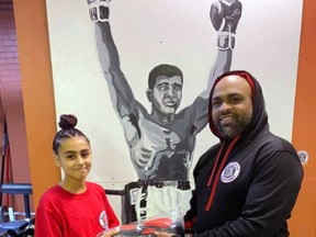 Brantford Black Eye Boxing Club member Winston (The Punisher) Matthews presents his daughter, Keya, with a pair of gloves. Keya was recently awarded the Patrick Campbell Pay it Forward Award.