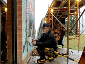 Kevin Wright, a facilities technician with the City of Brockville, installs a timer on Friday afternoon for the lights along a covered walkway people use to exit the COVID-19 assessment centre at the Memorial Centre. (RONALD ZAJAC/The Recorder and Times)