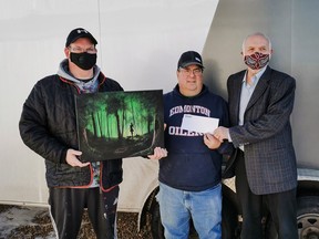 Shane Ellis Jordan, the artist behind HOPE, poses with top bidder Danny Povaschuk, who paid $325 for the piece, the proceeds of which are going to the Hanna Food Bank, represented by President Willard Edwards. Photo submitted by Jordan