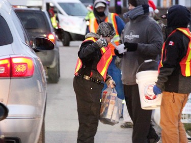 Volunteers collect donations for the Salvation Army at one of the entrances to the drive-thru parade. (Tyler Kula/The Observer)