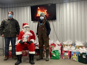 Schuyler Farms owner Brett Schuyler, Ronnie Cabie as Santa, and Schuyler's wife, Carrie Woolley, stand with gifts for the stranded migrant workers at the farm. (Supplied photo)