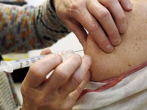 A nurse injects influenza vaccine Nov. 7, 2016 at Belleville General Hospital in Belleville, Ont.