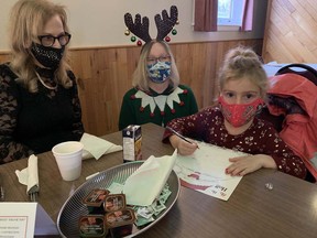 Sue Beland-Knibbs and her four-year-old grandaughter, Harper-Gracielee Anderson, are helped to their table by Jennifer Janeczko, one of many volunteers who helped serve Breakfast with Santa at the Polish Hall on Pearl Street on Sunday.