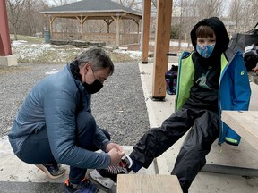 Nine-year-old Alexander Folprecht, of Elizabethtown-Kitley, gets some help from his dad, Paul, before heading onto the very busy Rotary Rink on Wednesday afternoon. The rink will close after Christmas as part of the provincewide lockdown. (RONALD ZAJAC/The Recorder and Times)
