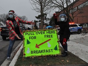 CCVS principal Jason Wagensveld and staff member Sheila MacIntyre did their best on Saturday December 12, 2020 in Cornwall, Ont. in order to attract motorists to this year's community breakfast.  Francis Racine/Cornwall Standard-Freeholder/Postmedia Network