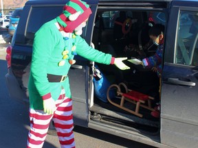 Santa got a part-time elf, mayor Jeff Genung, to help distribute sleds to deserving local preschoolers (this one had a letter to exchange) at a drive-thru event December 20 at Cochrane Toyota. Patrick Gibson/Cochrane Times