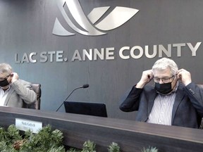 Reeve Joe Blakeman and deputy reeve Nick Gelych put on their masks in council chambers. The county has started an information campaign to encourage residents to follow the health regulations related to COVID-19.