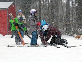 Some of the first skiers of the year get some help with their equipment, Saturday, at Laurentian Ski Hill. 
PJ Wilson/The Nugget