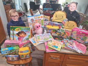 Jordyn Schellenberger (left), 8, and brother Mack, 7, of Mitchell pose with some of the gifts they were able to purchase this year through the Angel Tree program. Money raised for the purchases was hours of scouring the ditches and roadsides near their house, and it totalled $172.40.  Well done! SUBMITTED