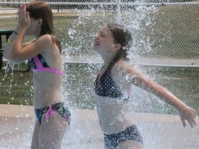 The fence bounding the Cox Youth Centre splash pad in Tecumseh Park could be disappearing as part of an upgrade project planned for 2021. Shayna White, 9, of Sarnia is pictured in this July 2012 file photo, cooling off under one of the sprinklers at the splash pad.
