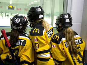 A trio of minor hockey players watch the action while waiting to hit the ice. (Free Press files)