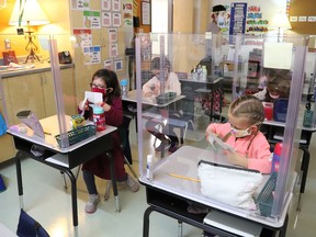 Joni McDonnell, left, and Molly Dodge participate in a school activity behind a plexiglass shield at MacLeod Public School in Sudbury, Ont. on Tuesday September 8, 2020.