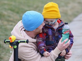 Kory Phair offers his son, Liam, 3, a drink after getting some exercise on a scooter in Sudbury, Ont. on Friday December 11, 2020.