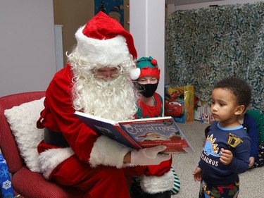 Santa Claus reads to children at Pitter Patter Daycare during a visit to the centre on Monday. Taking a closer look was Marcus.