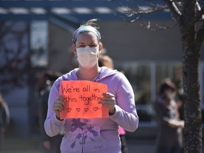 A member of hospital staff holds a sign that reads "We're all in this together" in front of the Woodstock Hospital on April 3, 2020. (Kathleen Saylors/Woodstock Sentinel-Review)