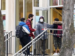 A staff member ensures students have done their health screening before entering Kelvin High School in Winnipeg on Wed., Dec. 2, 2020. Kevin King/Winnipeg Sun/Postmedia Network