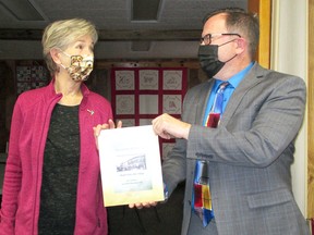 Julie Magerka, who wrote a book on local family histories called Memories of Merlin, presents Chatham-Kent Mayor Darrin Canniff, right, with a copy of the book on Dec. 1. Magerka's articles on family histories originally appeared in the Merlin Friendship Club newsletter since 2017. (Handout/Postmedia Network)
