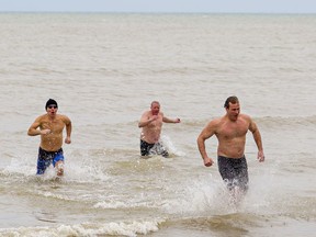 Rick Pierog (left) of Port Dover, Justin Geiser of Bills Corners and Tom Van Hooren of Vittoria were among a handful of people to brave the frigid waters of Lake Erie at Port Dover on Jan. 1. Brian Thompson/Postmedia Network