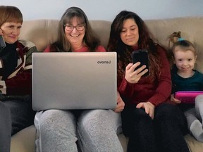 Demonstrating changes in technology are Lucy Marco (left) on a land-line phone, daughter Lee Ann Ferras, with a laptop, granddaughter Amanda Ferras, with a smart phone, and great-granddaughter Isla-Raye Hayes, with a tablet.