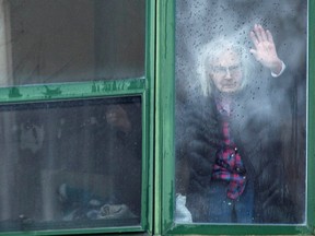 A resident waves from her window at Residence Herron, a senior's long-term care facility in the suburb of Dorval in Montreal. Many of those Canadians who haven’t travelled and have followed the suggested guidelines experience loneliness. REUTERS/Christinne Muschi