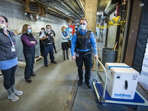 Pharmacy staff of Kingston Health Sciences Centre wait as a security guard stands next to the first shipment of the Pfizer-BioNTech COVID-19 vaccine for southeastern Ontario Jan. 12. Both it and Moderna's vaccine are in use in Hastings-Prince Edward.