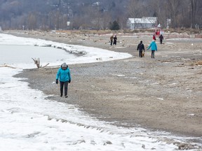 People walk the beach in Port Stanley on Jan. 25 where only a bit of ice has formed between the beach and open water. Sparse ice cover contributes to soil erosion, and other environmental harms, experts say. Derek Ruttan/Postmedia Network
