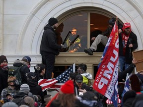 A mob of supporters of U.S. President Donald Trump climb through a window they broke as they storm the U.S. Capitol Building in Washington, U.S., January 6, 2021. REUTERS/Leah Millis/File Photo