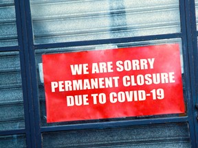 A sign in the window of a shop displaying the message "Permanent closure due to COVID-19."