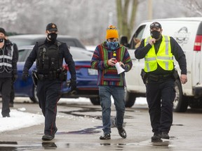 A protester who entered the property of the Church of God in Aylmer is escorted off the premises by Aylmer police on Sunday January 3, 2021. (Mike Hensen/The London Free Press)