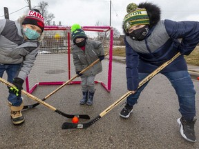 Xavier Anderson, 9, Bently Martin, 9, and Jace Martin, 4, got hockey sticks from two London police constables after the officers briefly joined their road hockey game on the weekend. (Mike Hensen/The London Free Press)