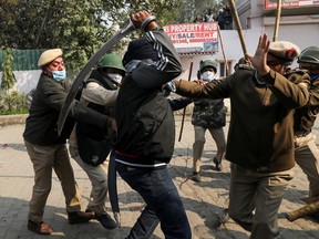 A man wields his sword against a policeman during a clash between protesting farmers and a group of people shouting anti-farmer slogans, at a site of the protest against farm laws at Singhu border near New Delhi, India January 29, 2021. REUTERS/Anushree Fadnavis