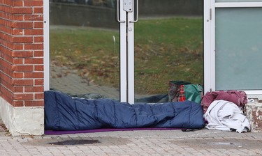 A person rests on the ground in front of doors at the Sudbury Community Arena in Sudbury, Ont. on Wednesday October 21, 2020. John Lappa/Sudbury Star/Postmedia Network