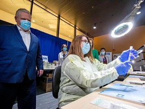 Ontario Premier Doug Ford watches a health-care worker prepare a Pfizer-BioNTech coronavirus disease (COVID-19) vaccine at The Michener Institute, in Toronto Monday. CARLOS OSORIO/REUTERS