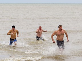 Rick Pierog (left) of Port Dover, Justin Geiser of Bills Corners and Tom Van Hooren of Vittoria were among a handful of people to brave the frigid waters of Lake Erie at Port Dover, Ontario on Friday January 1, 2021.