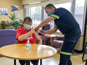 Paramedic Chris Takacs administers a COVID-19 vaccine to Cathy Vandesompele, a PSW at Norfolk Hospital Nursing Home, on Friday  in Simcoe.