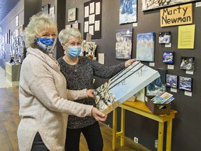 Artist Robbin Pulver-Andrews (left) shows one of her paintings to Marty Newman at the Capitol Arts Market in downtown Simcoe, Ontario on Saturday January 23, 2021. Brian Thompson/Brantford Expositor/Postmedia Network