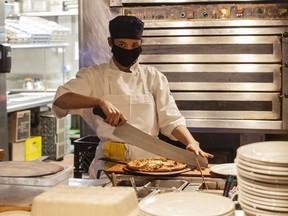 An employee at Earls Fort McMurray cuts pizza fresh from the oven on Friday, December 11, 2020. Photo courtesy Robert Murray