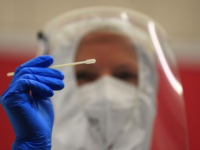 A health worker holds a swab at a COVID-19 test centre.