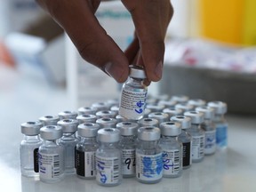 A health-care worker handles vials of Pfizer/BioNTech vaccine.