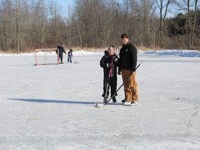 Jody Wales and his daughter, Karleigh, stand on the rink that Wales has built and maintained every winter for the past decade in their Napanee neighbourhood.