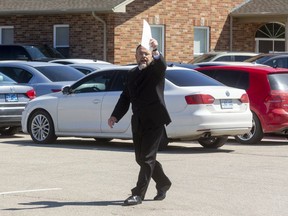 Pastor Henry Hildebrandt of the Church of God in Aylmer walks among his churchgoers, all seated in their vehicles. (Mike Hensen/The London Free Press)
