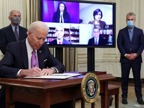 U.S. President Joe Biden signs an executive order as part of his administration's plans to fight the novel coronavirus pandemic during a COVID-19 response event as Dr. Anthony Fauci and COVID-19 czar Jeff Zients listen at the White House in Washington, D.C., on Thursday.